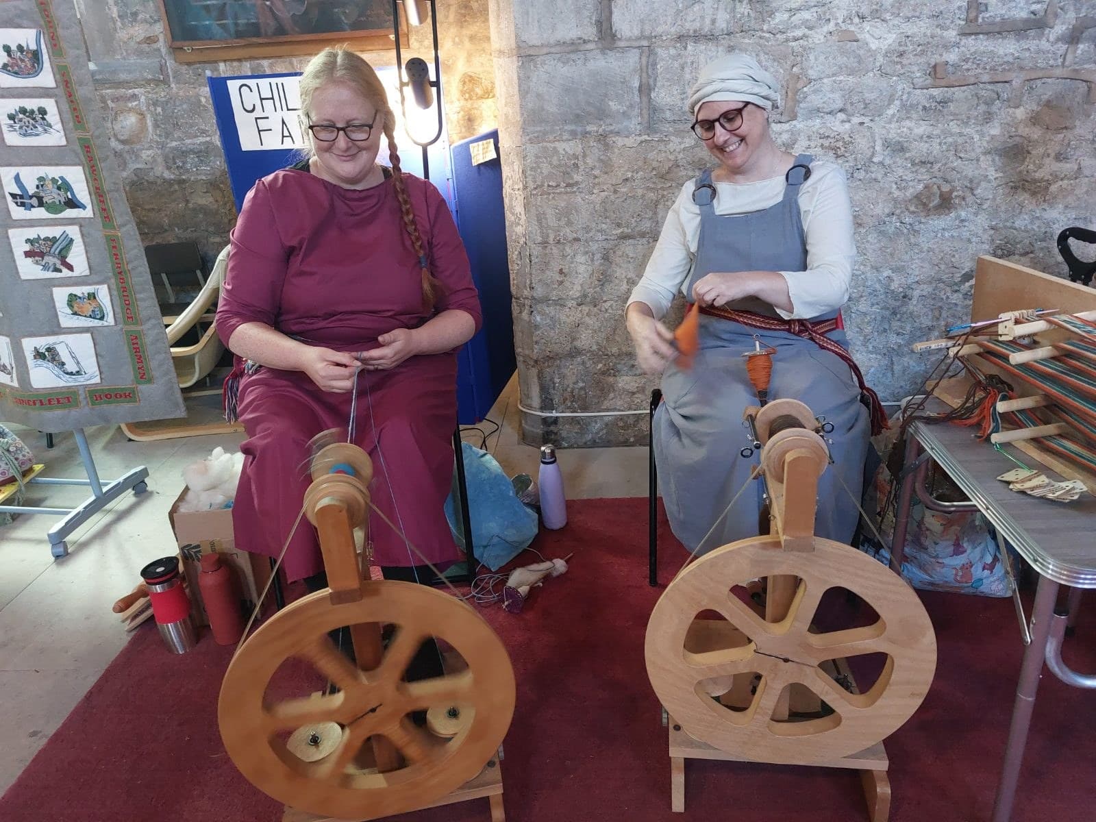 Two makers spinning yarn at traditional spinning wheels