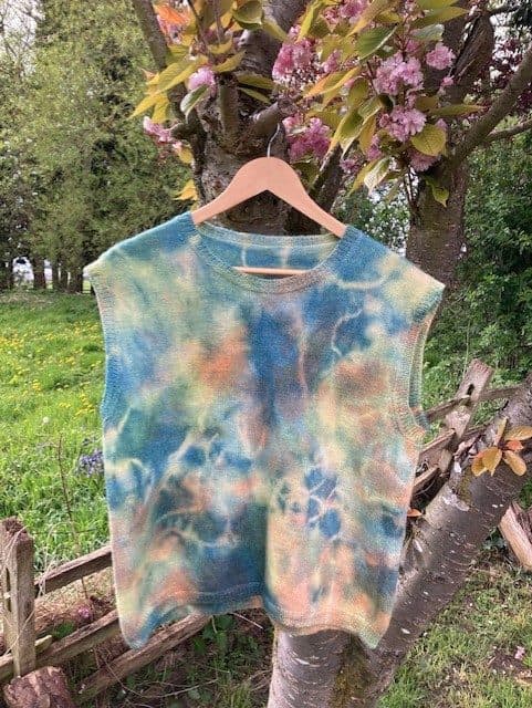A hand-knitted top dyed with homegrown plant dyes, hung in the orchard