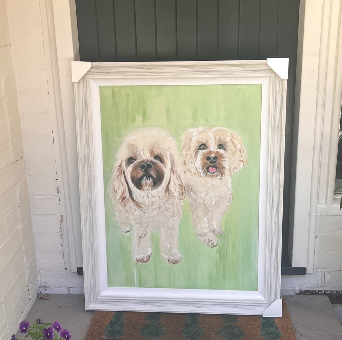 A framed painting of two dogs, propped against a wall