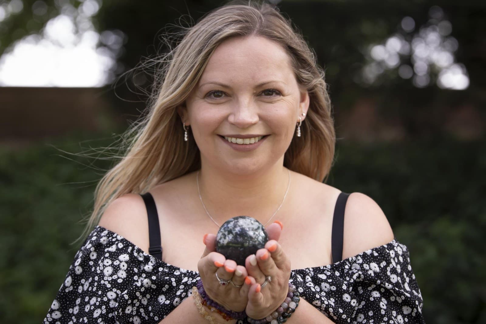 Keli outdoors, holding a crystal in cupped hands