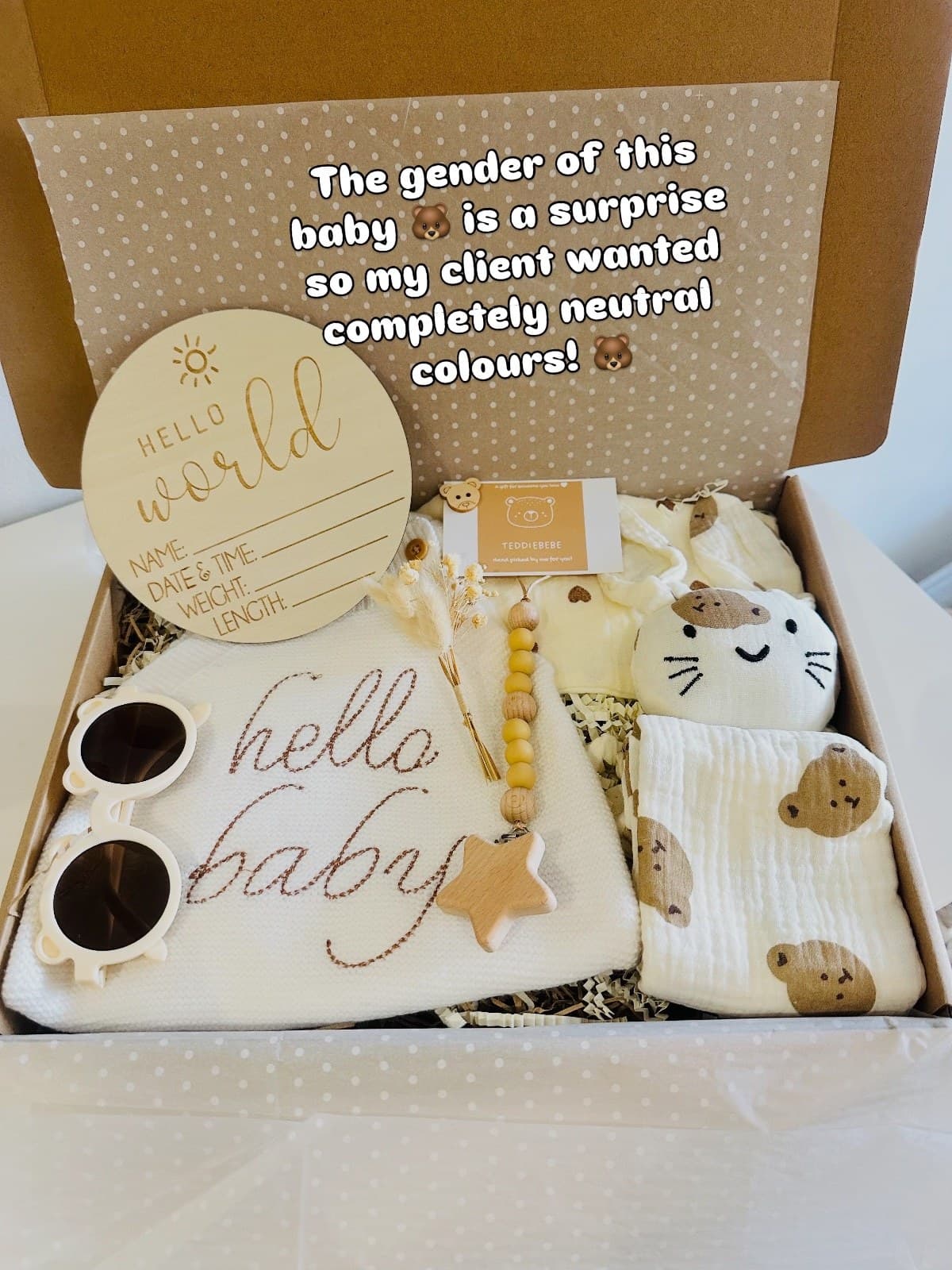 A neutral baby gift box with a hello world disc, socks and knitted pieces