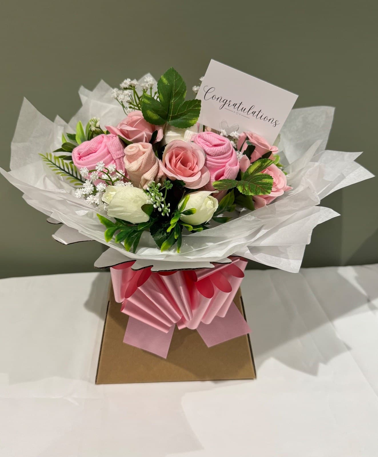 A bouquet of pink and cream roses wrapped as a congratulations gift